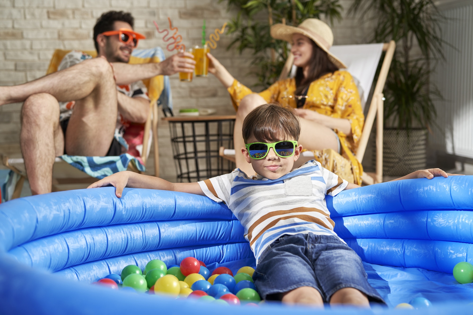 Portrait of boy in swimming pool and parents drinking drink