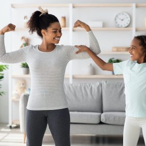 Strong african american mother and daughter showing their muscles
