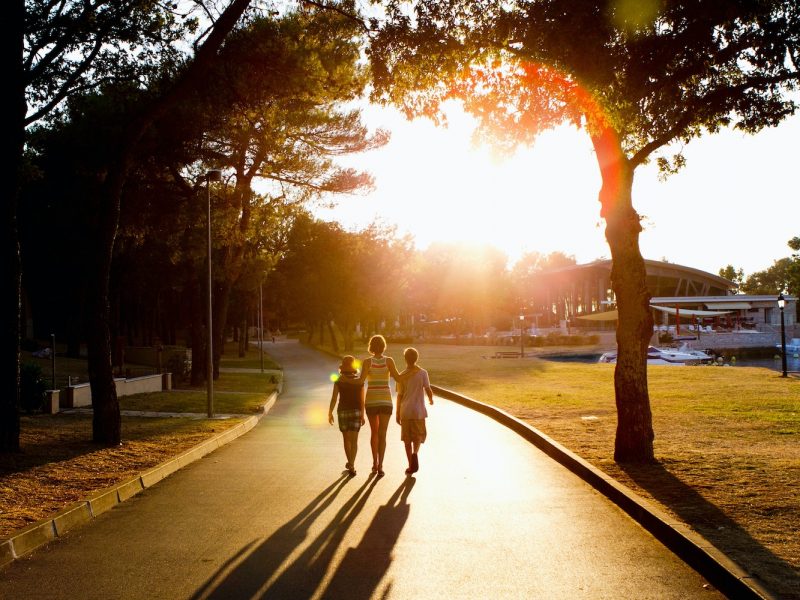 Mother and children walking on path in sunlight